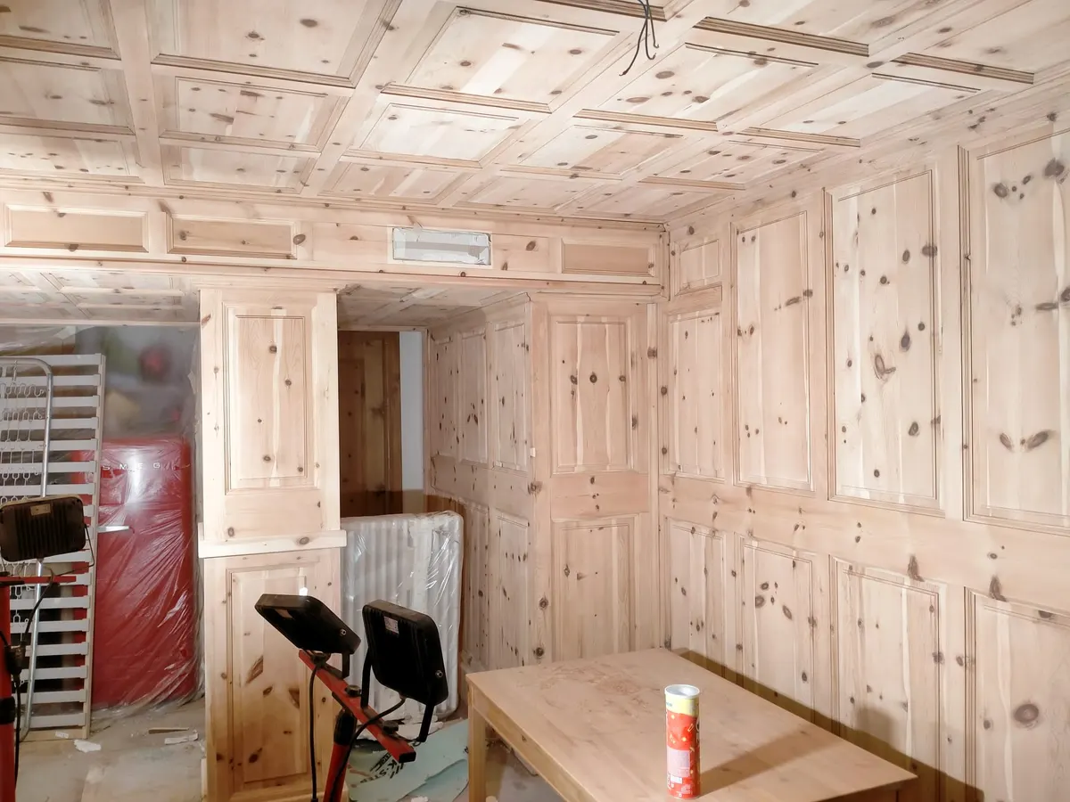 Raum mit hellem Holz und geometrisch geschnitztem Täfer